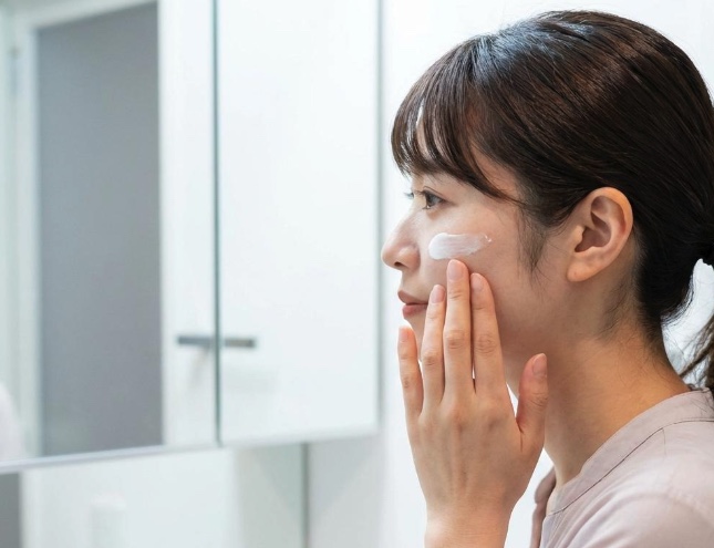 鏡の前で日焼け止めを塗っている女性