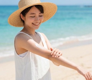 朝のスキンケアで日焼け止めを塗る女性