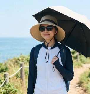 紫外線対策として日傘、帽子、長袖、サングラスをする女性